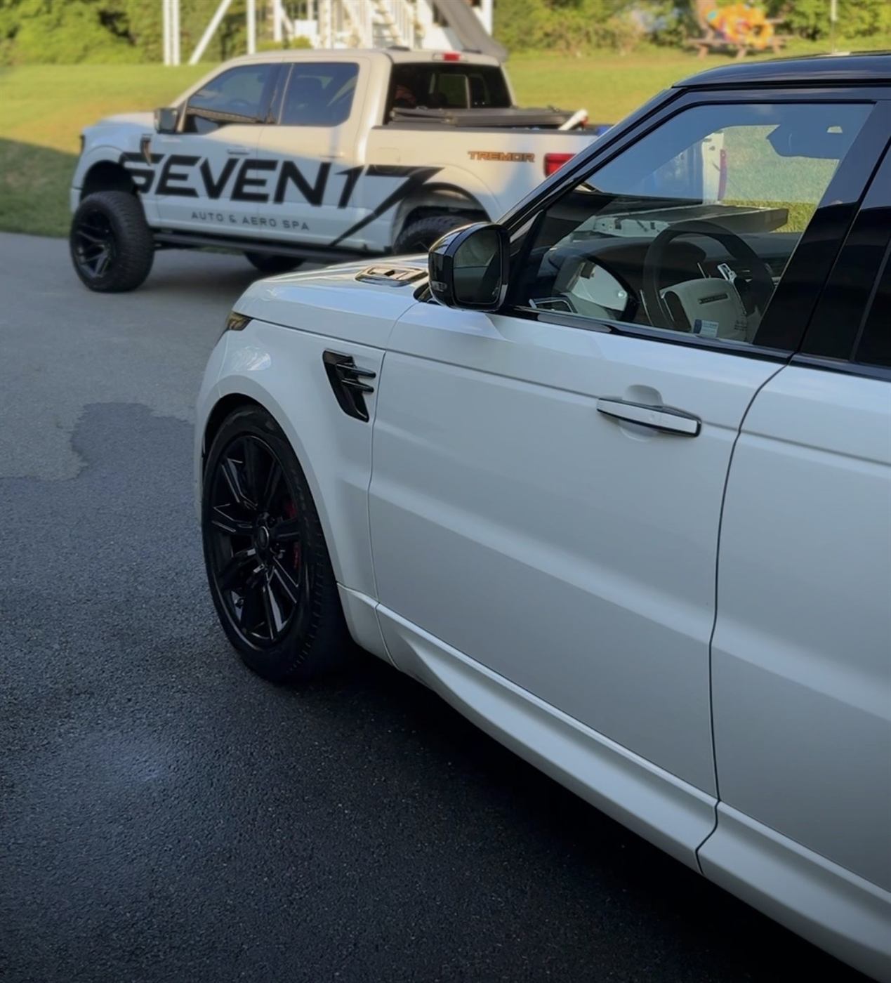 Detailed white Range Rover Sport parked on asphalt beside a Seven17 service truck