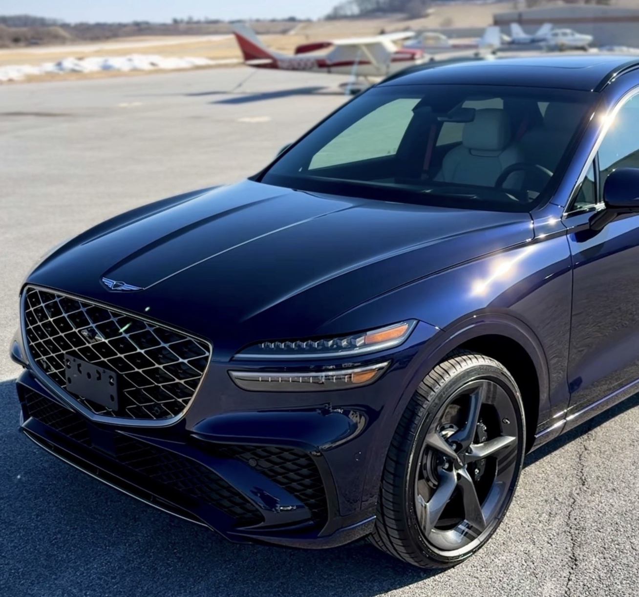 Detailed dark blue SUV on an airport ramp, aircraft parked behind